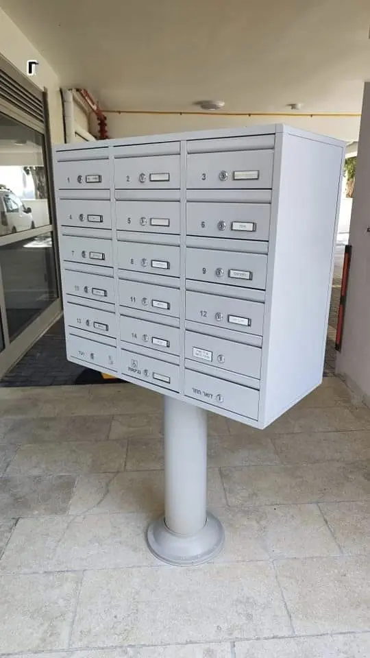 תיבות דואר מעוצבות לבניין, כוללות מקום לאינטרקום לבית פרטי, מותקנות על עמוד.