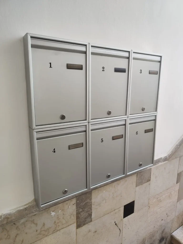 תיבות דואר מעוצבות לבית פרטי, מסודרות על קיר עם מספרים, עשויות מתכת אלומיניום מוברשת.