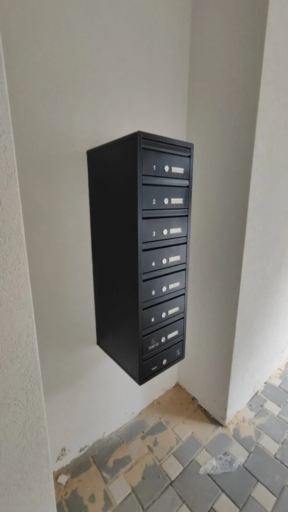 תיבת דואר מעוצבת לבית פרטי, עם מספר תאים, מותקנת על קיר באזור פנימי.